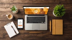 A flat-lay view of a wooden desk with a laptop, smartphone, notebook, and a cup of coffee, representing a digital business launch in India.